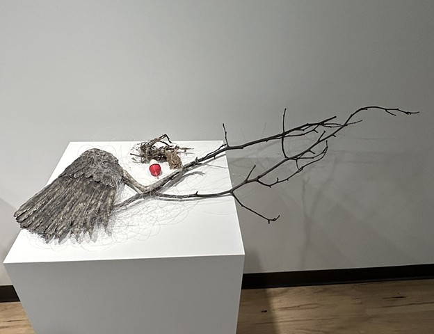 a still life sculpture with porcelain heron wing and leg, porcelain fishing bobber, and found branch, all entangled in fishing line and river debris