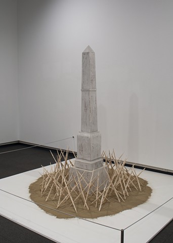 Stylized monument based on local Confederate memorial, surrounded by grasses dipped in porcelain, burned away, and assembled into caltrops, resting on a bed of ashes.