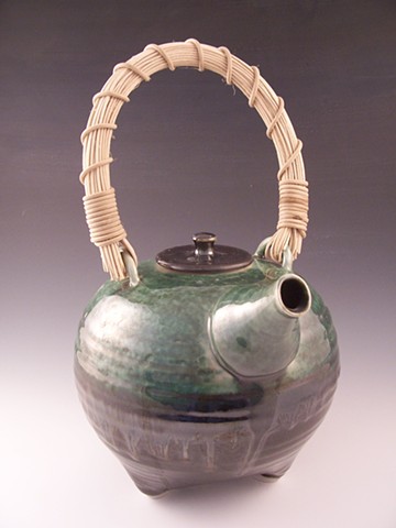 Three-legged tripod teapot with cane handle.