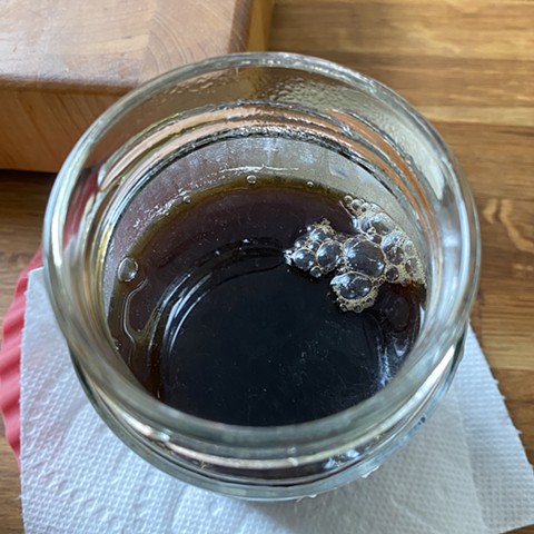 Ink is filtered into a clean glass jar. Adding a clove can help keep the liquid from going moldy. I store all my handmade inks, labeled with the ingredients and date, in the fridge.