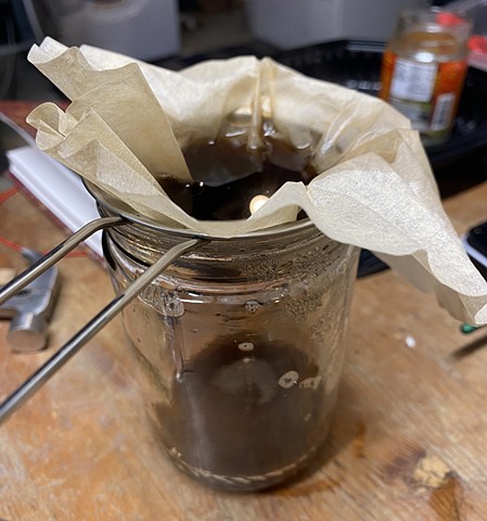 Straining magnolia seed pod ink through a coffee filter