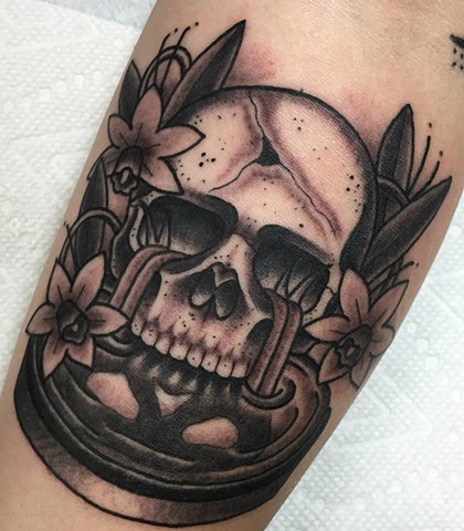 Black and grey traditional skull tattoo with daffodil flowers and water. Made in Toronto