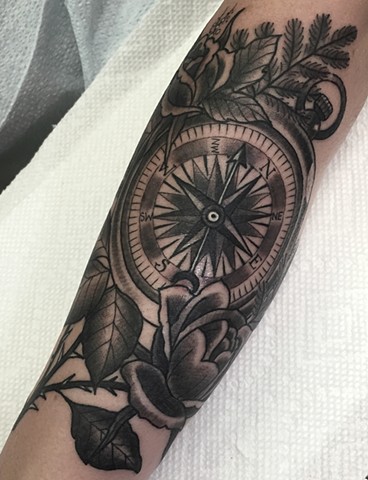 Detailed compass tattoo with rose floral on the arm, in black and grey traditional tattoo style, made in Toronto