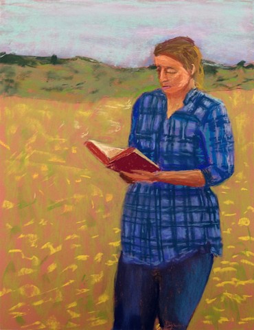Young woman reading while walking in a field of flowers