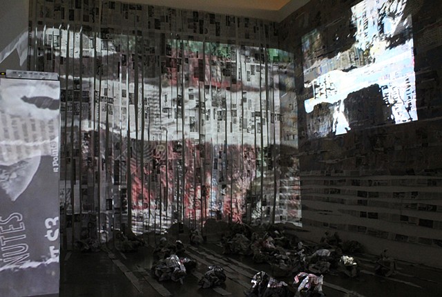 Palimpsest: An installation composed of 1) two video pieces (one projected on a wall and the other one projected on a "curtain" of torn newspapers) and 2) crumpled newspaper "balls" on the floor with parts of projection on them