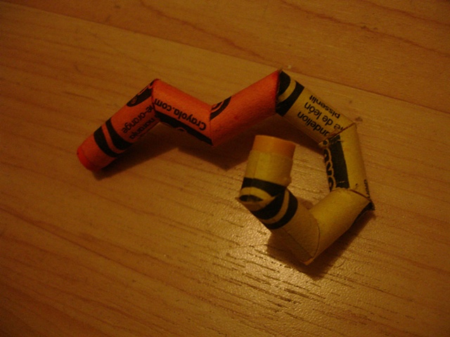 a yellow-orange crayola crayon molting into dandelion
