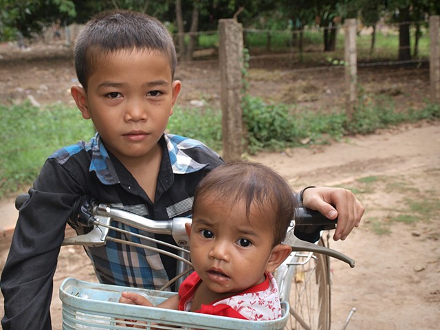 Boy carrying sister in handlebar basket