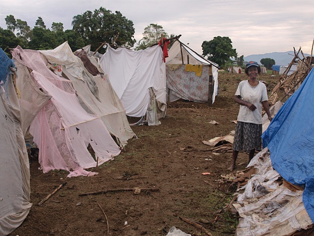 Woman in Leogane tent camp among shelters from bed sheets