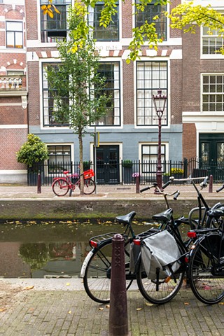 Scene with a red bicycle parked in front of a typical Amsterdam house