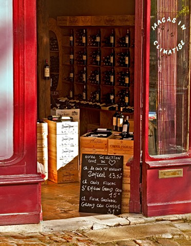 red walls on a St Emilion France wine store, wine crates and bottles on the walls, chalkboard sign