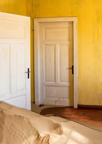 Brilliant yellow and sand coming in through a door in Kolmanskop