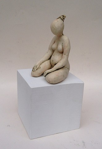 pale figurine sitting on white wooden cube