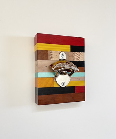 Modern wall mounted bottle opener with handmade salvaged wood backing.