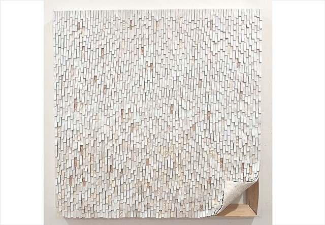 Peel by Julee Latimer is a contemporary wall sculpture featuring a square artwork on stretched canvas with one corner lifted to reveal the underlying timber stretcher and white plaster.  Covered with meticulously layered narrow strips of paint in white, iridescent white, metallic white and interspersed with golden wallpaper 