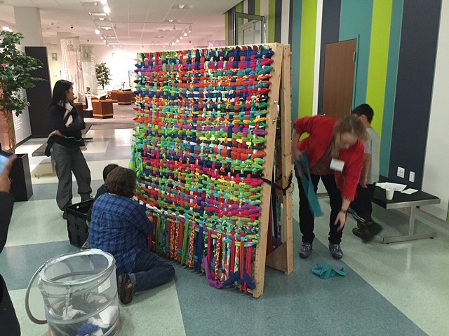 Visitors working on a large weaving during Young Audiences of Western NY's holiday party , 2016