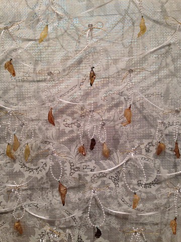 detail of chrysalises on string of plastic pearls