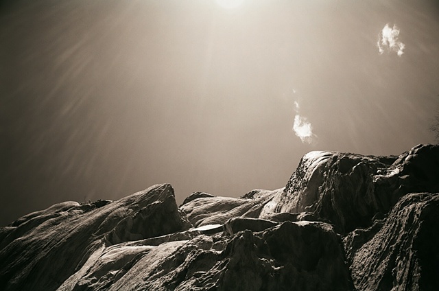 hanging rock black and white with rock in bottom and sun upper center horizontal.