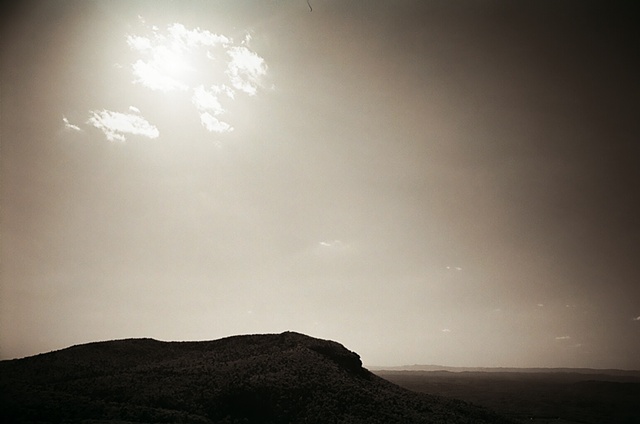 hanging rock black and white with sun upper left behind clouds. 