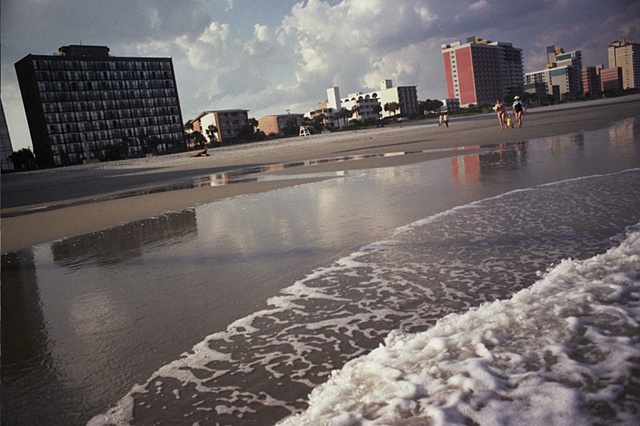 east coast with two women swinging child and water coming in in foreground.