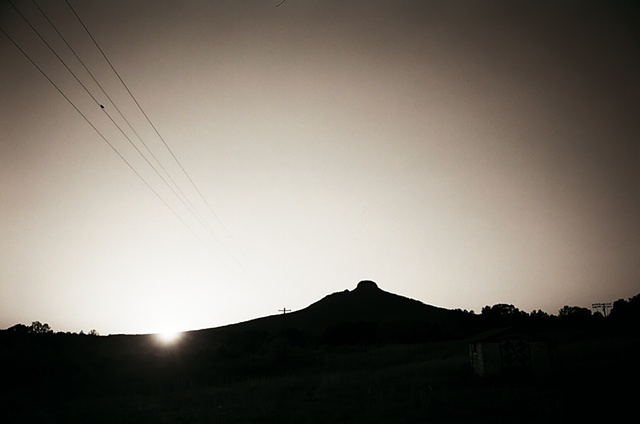 pilot mountain with visible sun and bird on powerlines centered.