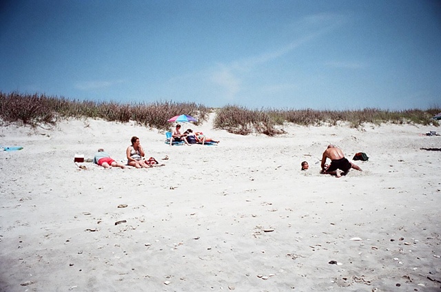 east coast father burying child in sand. 