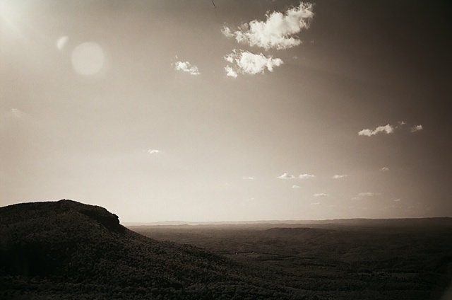 hanging rock black and white sun in upper corner with clouds to right horizontal. 