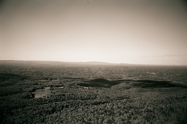 hanging rock black and white cloud shadow in distance by farm. 