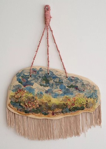 Searching for amulets... A landscape rendered in ceramic becomes a site of refuge and memory, a place to return to. The fiber speaks to the body, to labor, and to the intimate rituals of home and tradition. It also echoes the presence of fiber in sacred objects, where material and meaning are tightly woven. The knotted threads and fringe reference Tzitzit, a ritual practice that ties seeing to remembering. By framing the landscape with these fiber elements, the piece becomes a kind of visual prayer, where the natural world is made sacred. It becomes an amulet, a vessel of protection, devotion, and presence.
