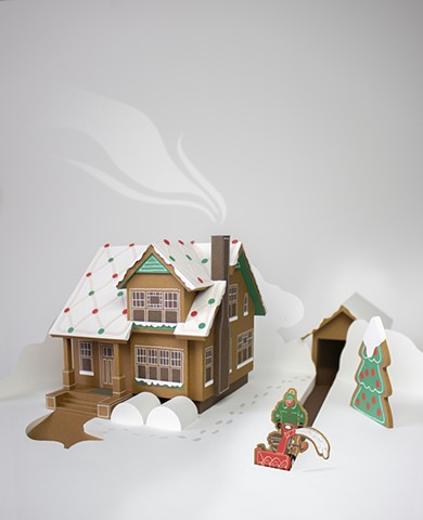 A cut paper gingerbread house and a cookie man snowblowing his driveway.