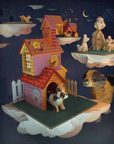 A collection of vintage dog figurines sit on top of cut paper clouds and dog houses