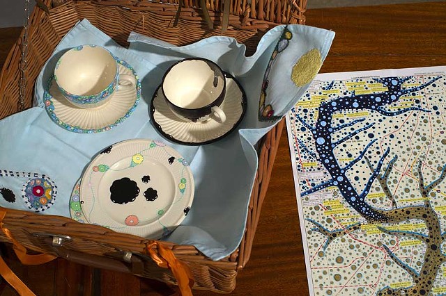 RIVER CAMPAIGN: Partial contents of River Campaign Picnic Basket: hand-painted china, hand-embroidered napkins, and hand-painted flatware
