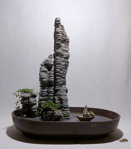 feather rock fountain of volcanic rock towers with mist, plants, and ceramic miniatures