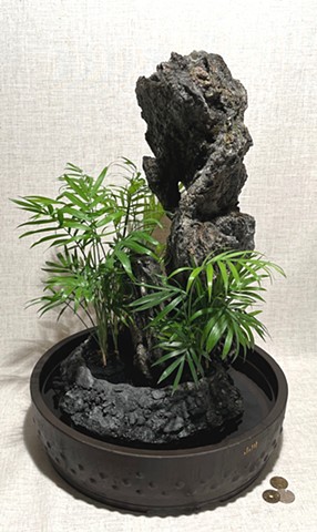a tall feather rock fountain with live ferns at the base