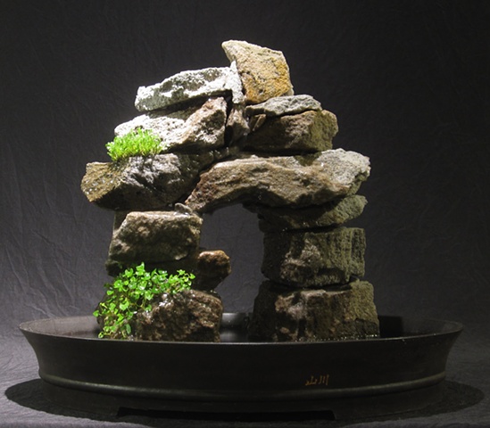 stone arch inuksuk with waterfall and plants