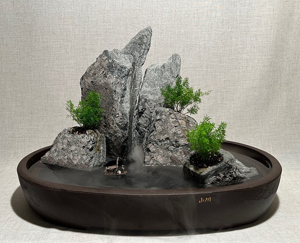 A tabletop fountain with five rock islands, live plants, a waterfall, mist, and a miniature boat