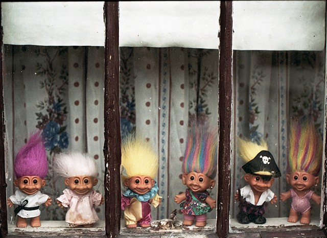 Troll dolls  with brightly colored hair and costumes in the window of a house in Avondale photographed by Lucy Mueller