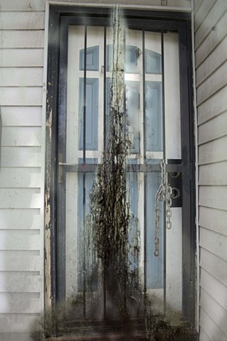 Composite of a door chained from the outside with a black spooky smoky appearance in front of it photographed by lucy mueller