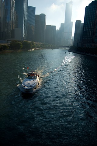 Power boat on the Chicago River surrounded by skyscrapers by lucy Mueller Photography