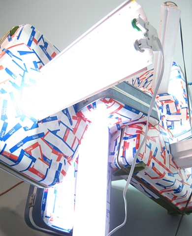 Detail
Title/Materials: Suitcases, Fluorescent Fixtures, Fluorescent Bulbs, Name Badge Stickers, Electrical Receptacles, Electrical Wiring and Box