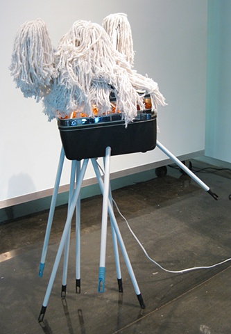 Title/Materials: Mops, Makeup Case, Artificial Flowers, Light Fixture, Light Bulb, Paint, Sawdust, Wood Glue