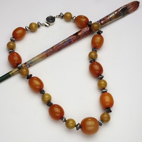 vintage orange celluloid beads are complimented with yellow jade and silver beads, this 23" necklace is finished with a silver box clasp (#899)
