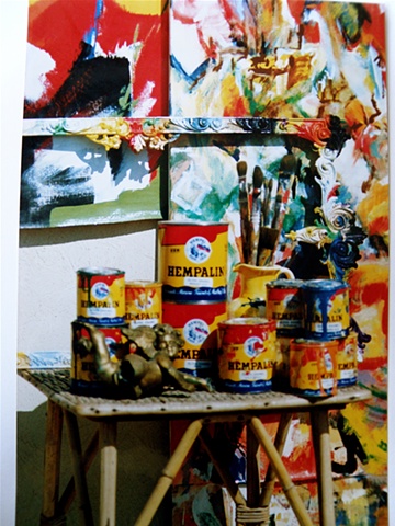 several paint cans, studio angel, brushes, mirror frame and paintings
