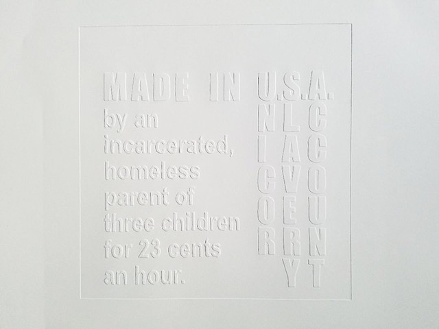 TAG series – triptych featuring three framed hand-embossed and painted paper works depicting a “Made in USA” clothing label commenting about wage deficient labor abuse of the incarcerated.