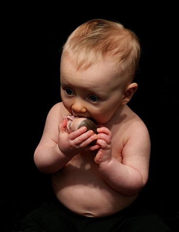 Photograph of a baby mouthing a small sculpted head 