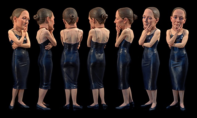 life-sized polychromed figurative sculpture of a woman in a tight dress wearing an oversized prosthetic head posed as if she is looking at something