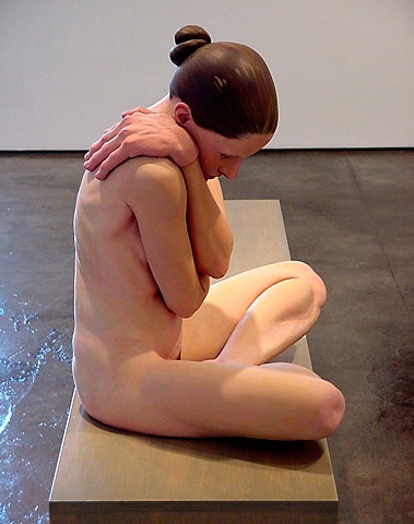 smaller than life=-size polychrome figurative sculpture of a seated nude woman with oversized glove like hands