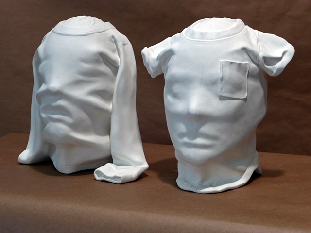 polyester resin figurative sculptures of a man and a woman's head covered in baby shirts