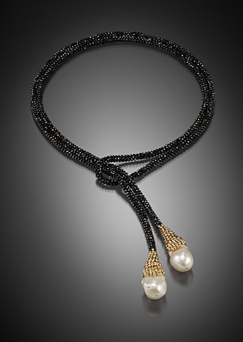 The lariat is hand-woven from black spinel and 14k gold beads with two freshwater pearls.