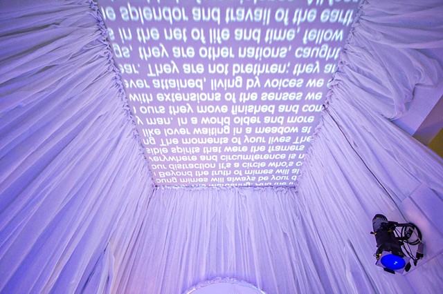 Installation view of backwards scrolling text, projected onto ceiling