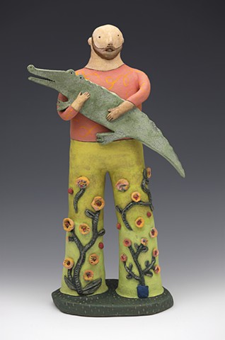 Bearded man in flowered pants plays on his alligator